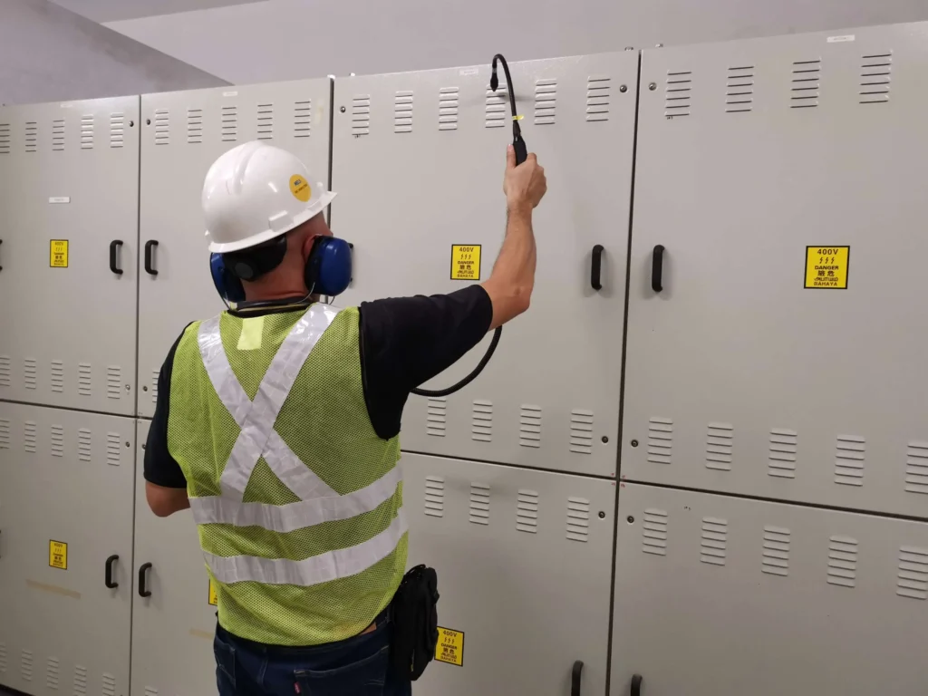 Technician conducting an airborne ultrasound inspection of industrial electrical switchgear