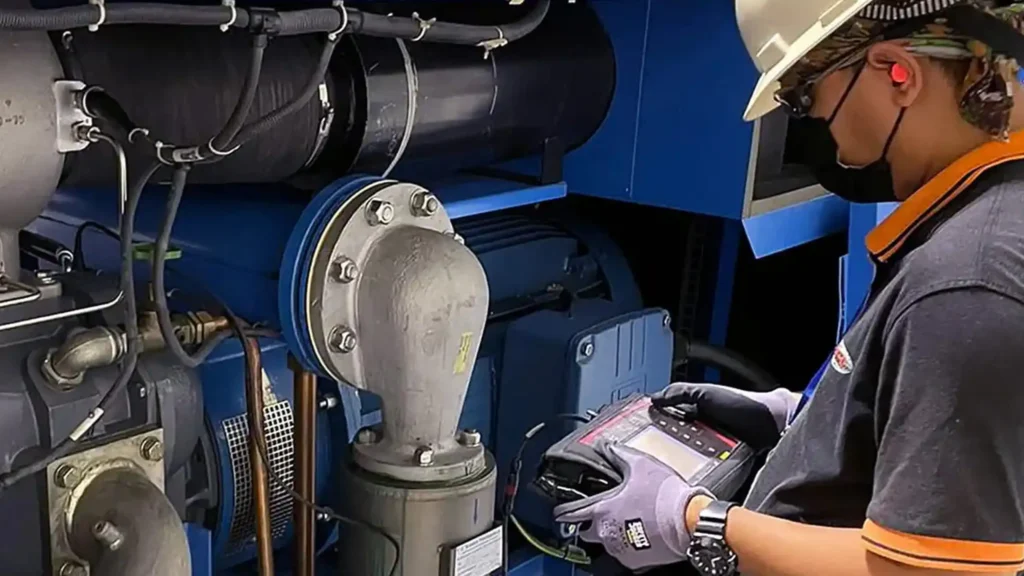 Technician using a handheld vibration analyzer to inspect industrial rotating equipment for machinery vibration testing and analysis.