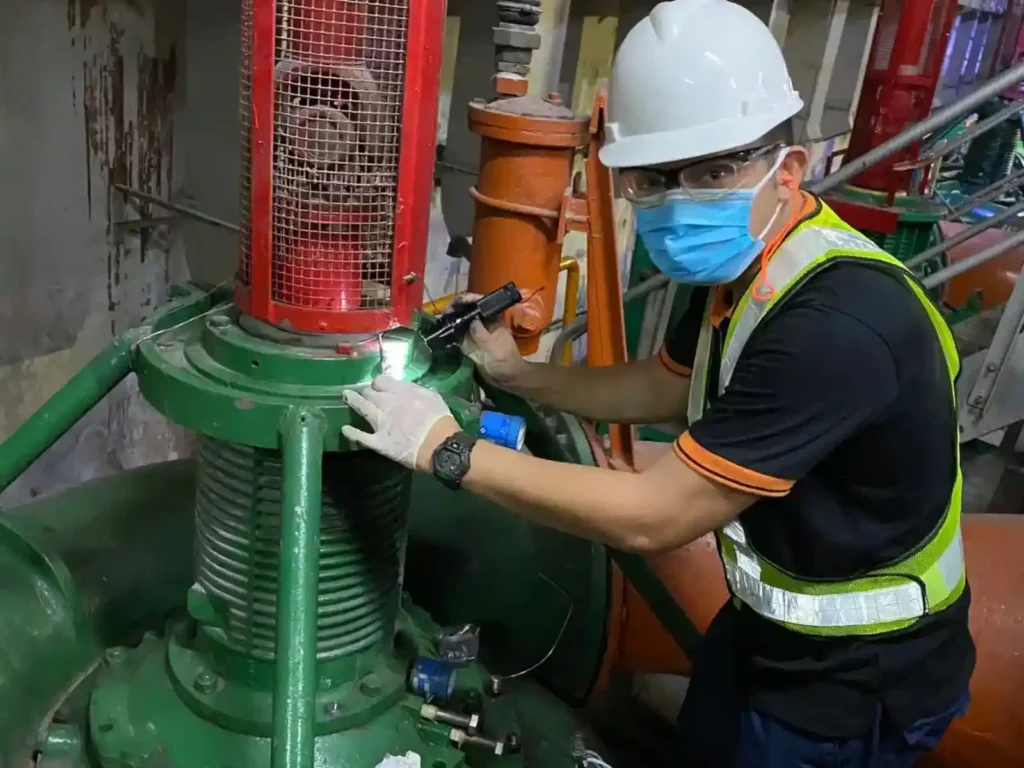 Maintenance technician inspecting the bearing housing of a vertical industrial pump