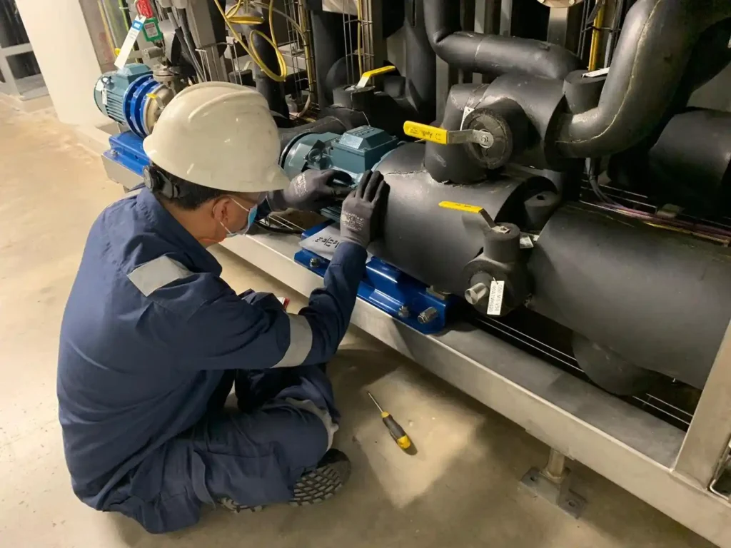 Maintenance technician inspecting an electric motor on an industrial chilled water pump system